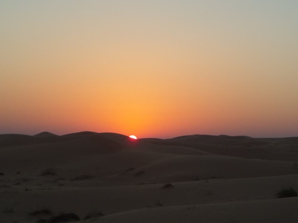 A picture of the sun setting over the dunes